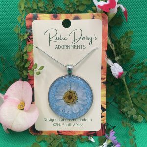 Large round silver coloured pendant with blue background and white Daisy