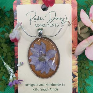 Large oval silver coloured pendant with metallic orange background and purple flower