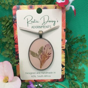 Large oval bronze coloured pendant with dusty pink background and Inca Lily petal with fern leaves