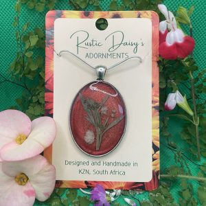 Large oval silver coloured pendant with metallic red background and white Baby Breath flowers with leaves