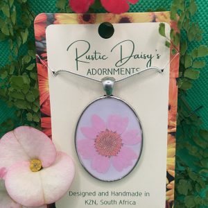 Large oval silver coloured pendant with white background and pink flower