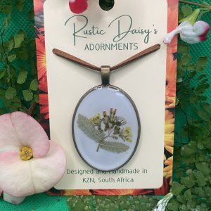 Large oval bronze coloured pendant with white background and small yellow flowers with leaves