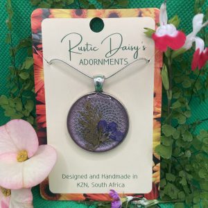 medium-large-round-silver-coloured-pendant-with-lilac-background-and-purple-flower-with-fern-leaf