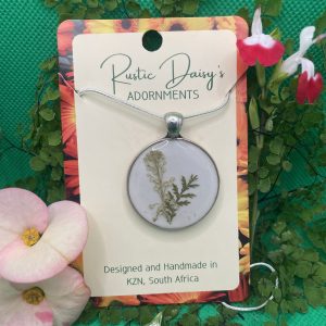 medium-large-round-silver-coloured-pendant-with-white-background-and-sprig-of-white-wild-flowers-with-fern-leaf