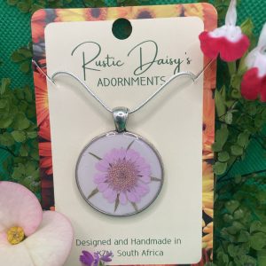 medium-large-round-silver-coloured-pendant-with-white-background-and-pink-daisy-with-sprigs-of-leaves