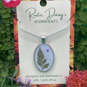 medium-oval-silver-coloured-pendant-with-white-background-and-fern-leaf-with-tiny-pink-flower