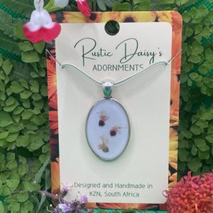 medium-oval-shaped-silver-coloured-pendant-with-white-background-and-pink-and-white-basil-flowers