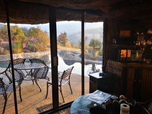 Rustic holiday room overlooking a swimming pool and mountains in the late afternoon
